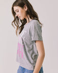 Side view of woman wearing Chaser’s Streaky Grey Love Tee with pink text on a white background