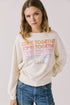 Front view of woman wearing Chaser’s The Beatles Come Together Starry White Long Sleeve with ‘COME TOGETHER’ text in rainbow colors on a plain background