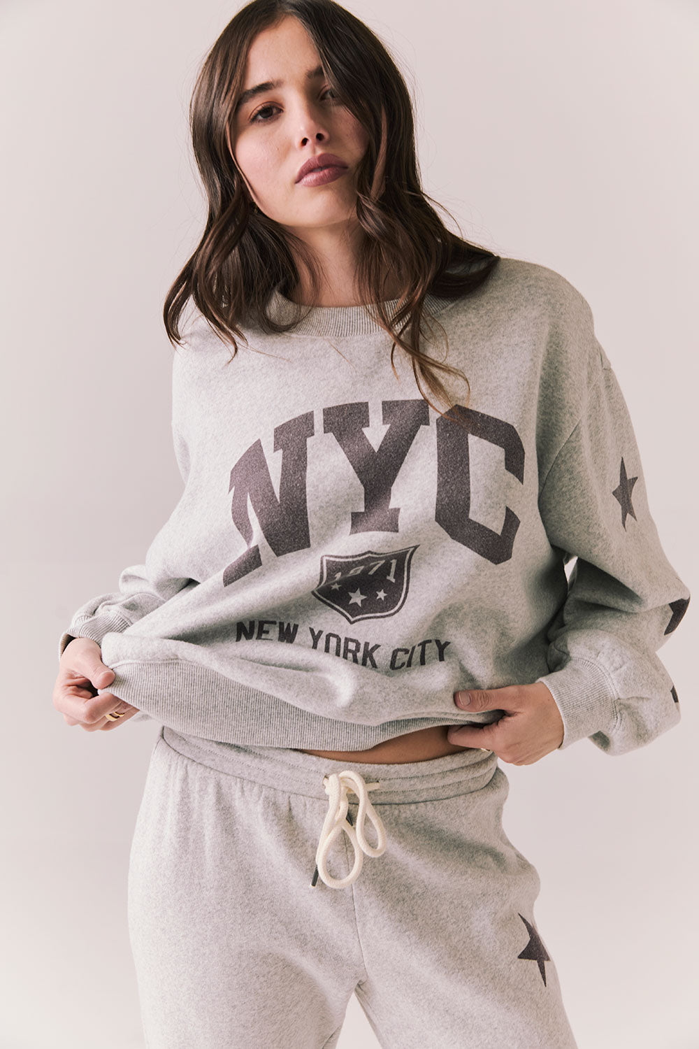 Front view of NYC Stars Pullover in Heather Grey with bold chest lettering and black star sleeves against a plain background