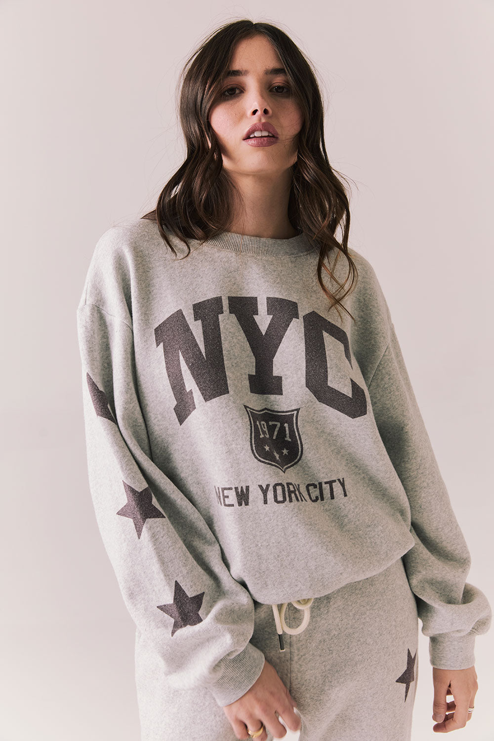 Front view of NYC Stars Pullover in Heather Grey with bold chest lettering and black star sleeves against a plain background