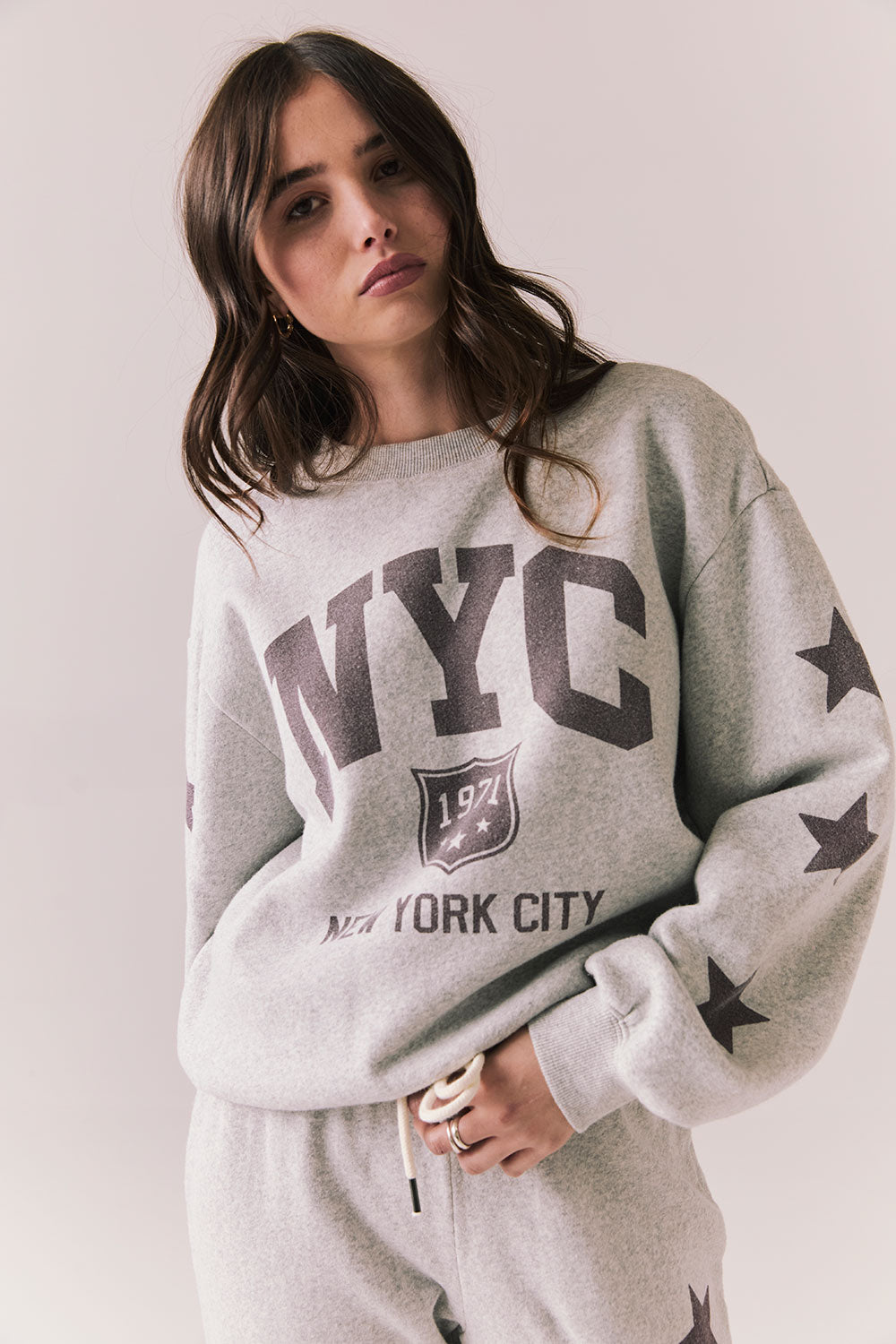 Front view of NYC Stars Pullover in Heather Grey with bold chest lettering and black star sleeves against a plain background
