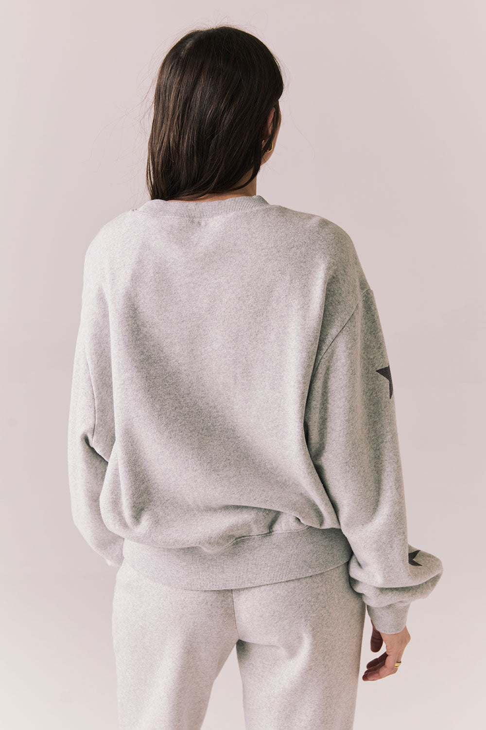 Back view of NYC Stars Pullover in Heather Grey with bold chest lettering and black star sleeves against a plain background