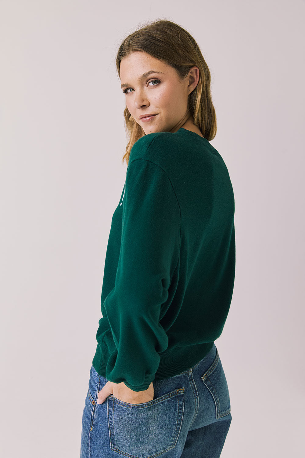 Back view of woman wearing Chaser’s green Cin Cin! Long Sleeve with “Cin Cin” text and star graphics on a plain background