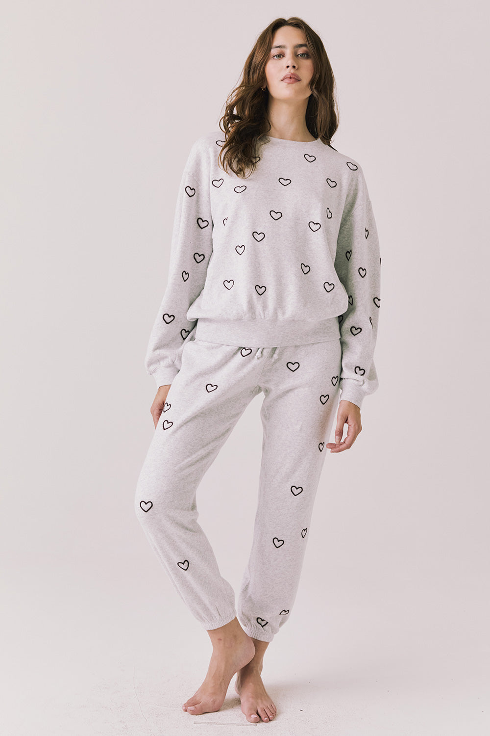 Full body view of woman wearing Chaser’s light grey Tossed Hearts Long Sleeve with matching Tossed Hearts Joggers on a white background