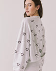 Back view of woman wearing Chaser’s light grey Tossed Hearts Long Sleeve with heart design on a white background