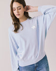 Front view of woman wearing Chaser’s Light Blue Love Stars Stitches Pullover Long Sleeve with star designs on a plain background