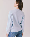 Back view of woman wearing Chaser’s Light Blue Love Stars Stitches Pullover Long Sleeve with star designs on a plain background