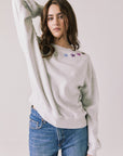 Front view of woman wearing Chaser’s Star Chainstitch Light Grey Long Sleeve with embroidered stars on a plain background