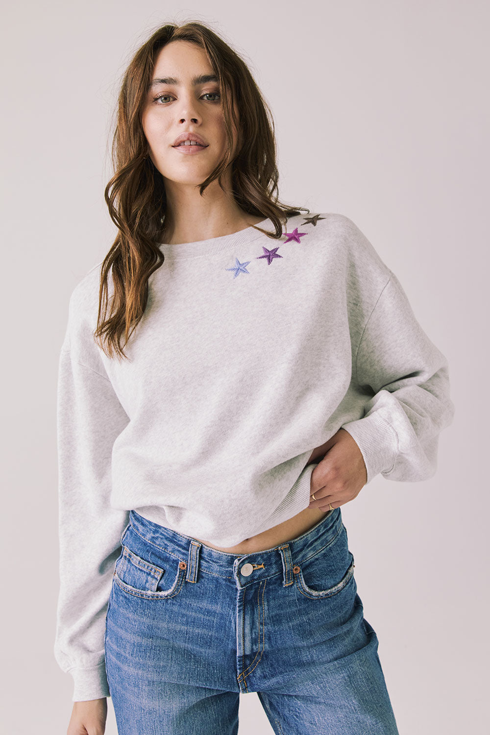 Front view of woman wearing Chaser’s Star Chainstitch Light Grey Long Sleeve with embroidered stars on a plain background