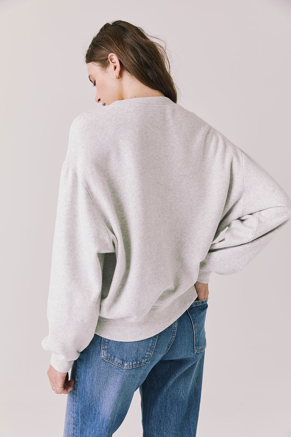 Back view of woman wearing Chaser’s Star Chainstitch Light Grey Long Sleeve on a plain background