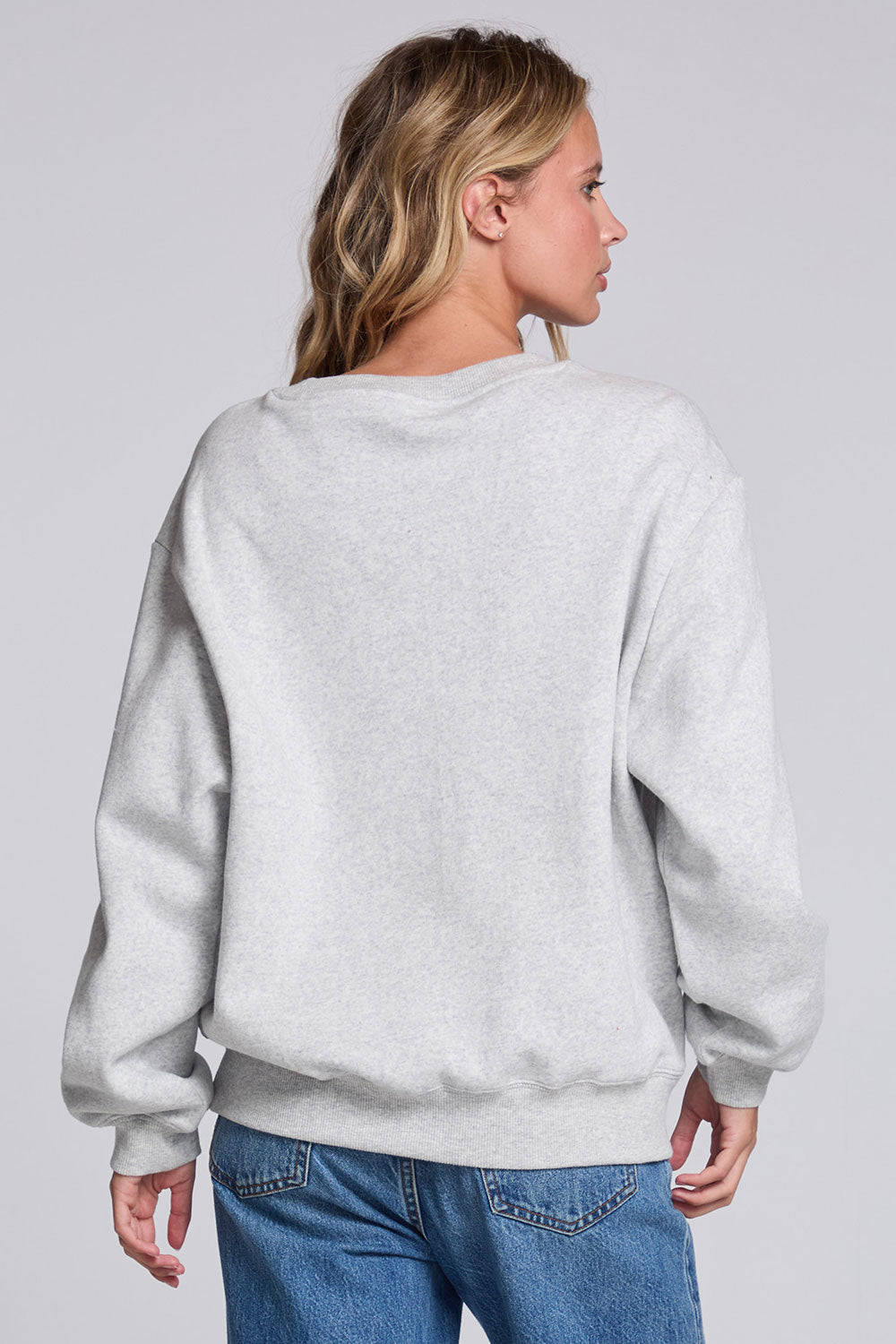 Model wearing Chaser's Merry Bow Pullover in Heather Grey with oversized red bow artwork, back view