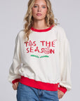 Model wearing Chaser's 'Tis the Season Pullover in Whisper White with red and green 'Tis the Season lettering and red trim, front view