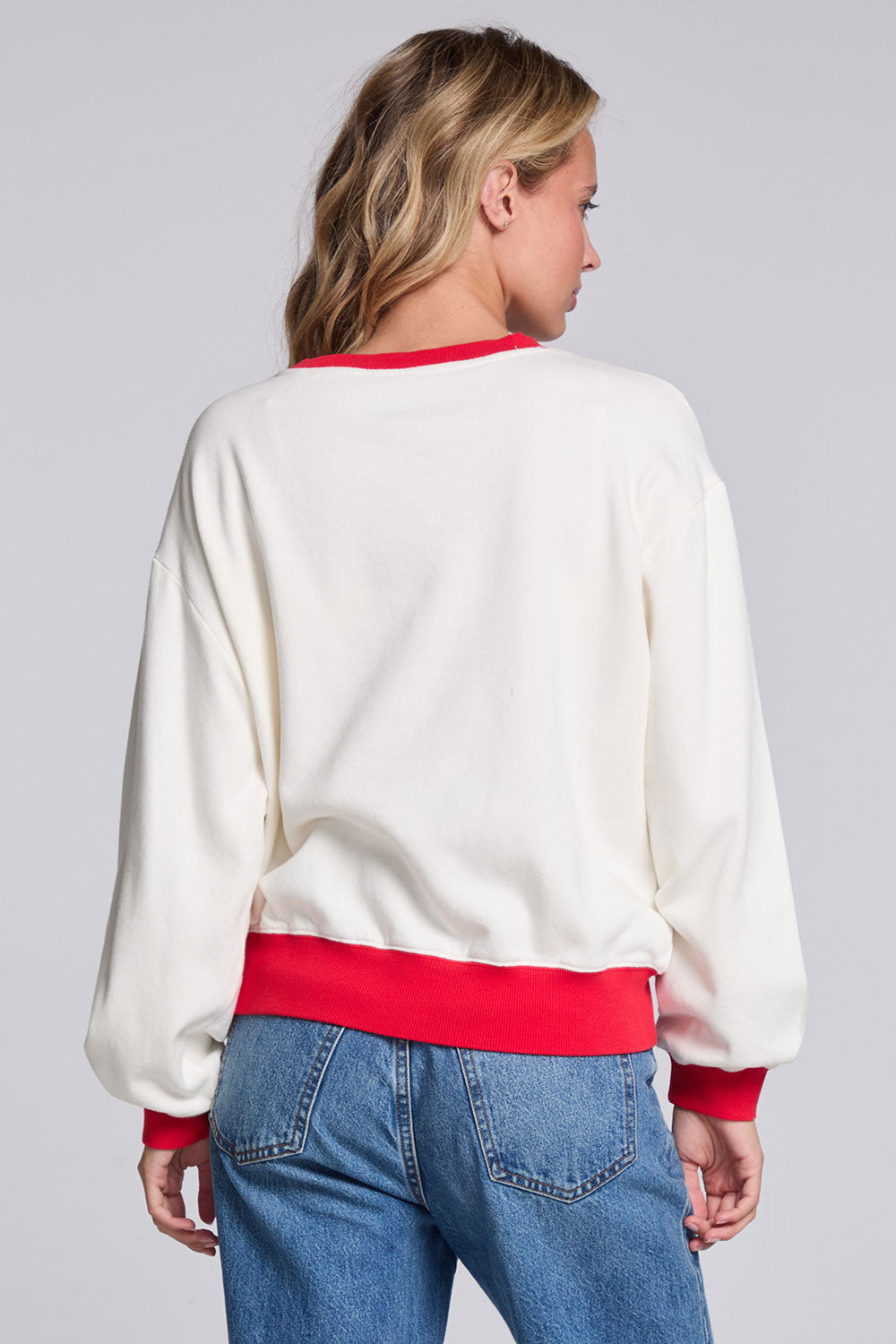 Model wearing Chaser's 'Tis the Season Pullover in Whisper White with red and green 'Tis the Season lettering and red trim, back view