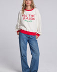 Model wearing Chaser's 'Tis the Season Pullover in Whisper White with red and green 'Tis the Season lettering and red trim, full-body view