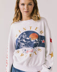 Front view of woman wearing Chaser’s white Coca-Cola Winter Sports Long Sleeve with vintage-inspired graphic design and blue jeans on a plain background