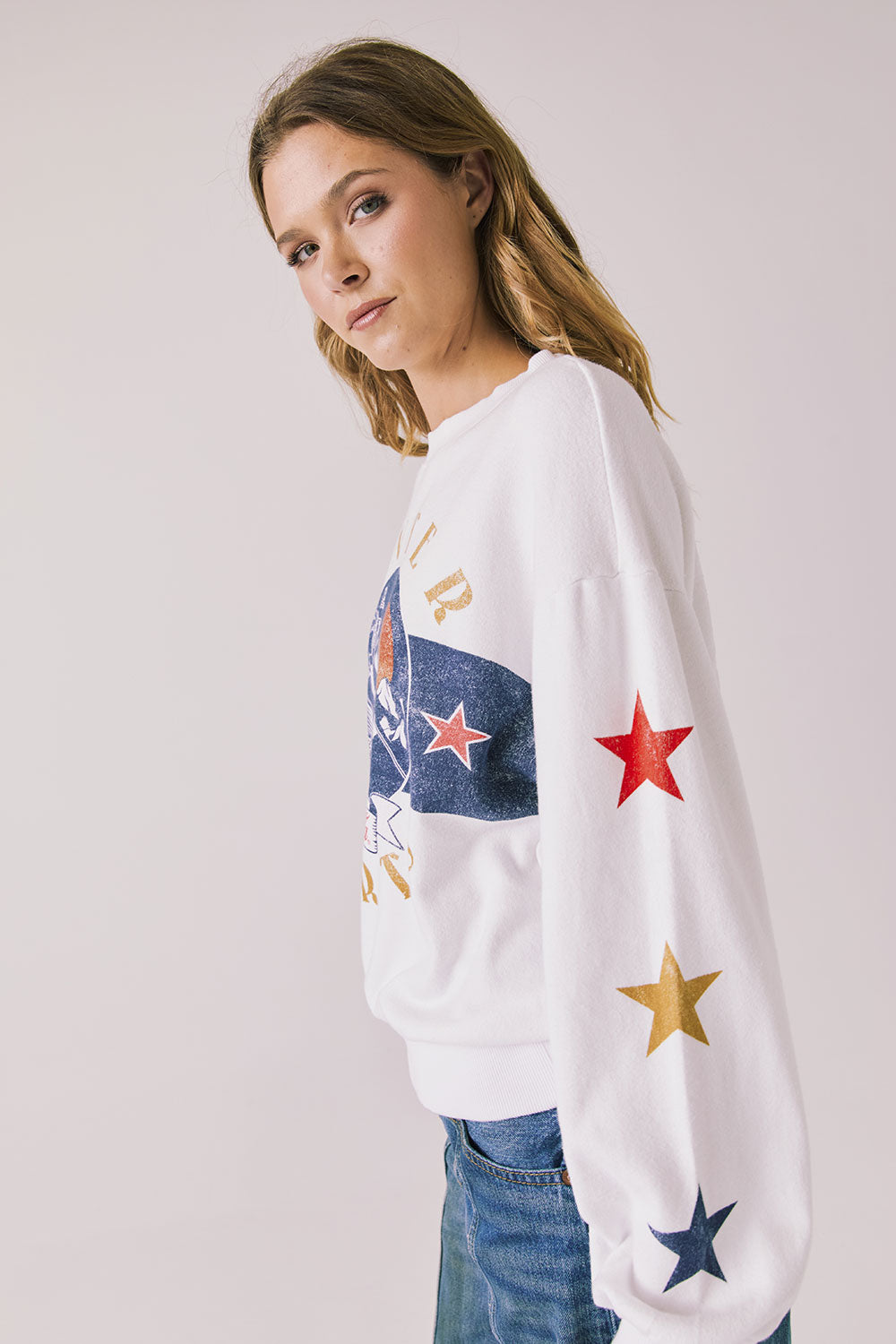 Side view of woman wearing Chaser’s white Coca-Cola Winter Sports Long Sleeve with vintage-style print on a plain background