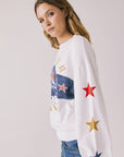 Side view of woman wearing Chaser’s white Coca-Cola Winter Sports Long Sleeve with vintage-style print on a plain background