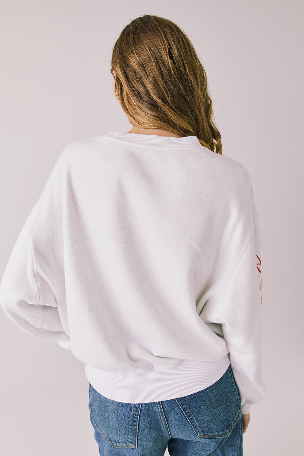 Back view of woman wearing Chaser’s white Coca-Cola Winter Sports Long Sleeve on a plain background