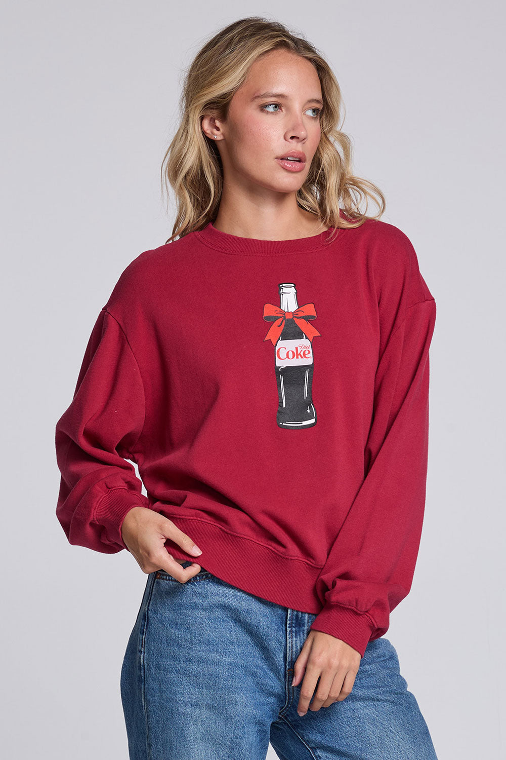 Model wearing Chaser's Coca-Cola Holiday Coke Pullover in Winter Garnet red with vintage Coca-Cola bottle artwork, angled view