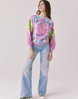  Full body view of woman wearing Chaser’s Grateful Dead Rose Logo Long Sleeve tie-dye top with blue jeans on a plain background