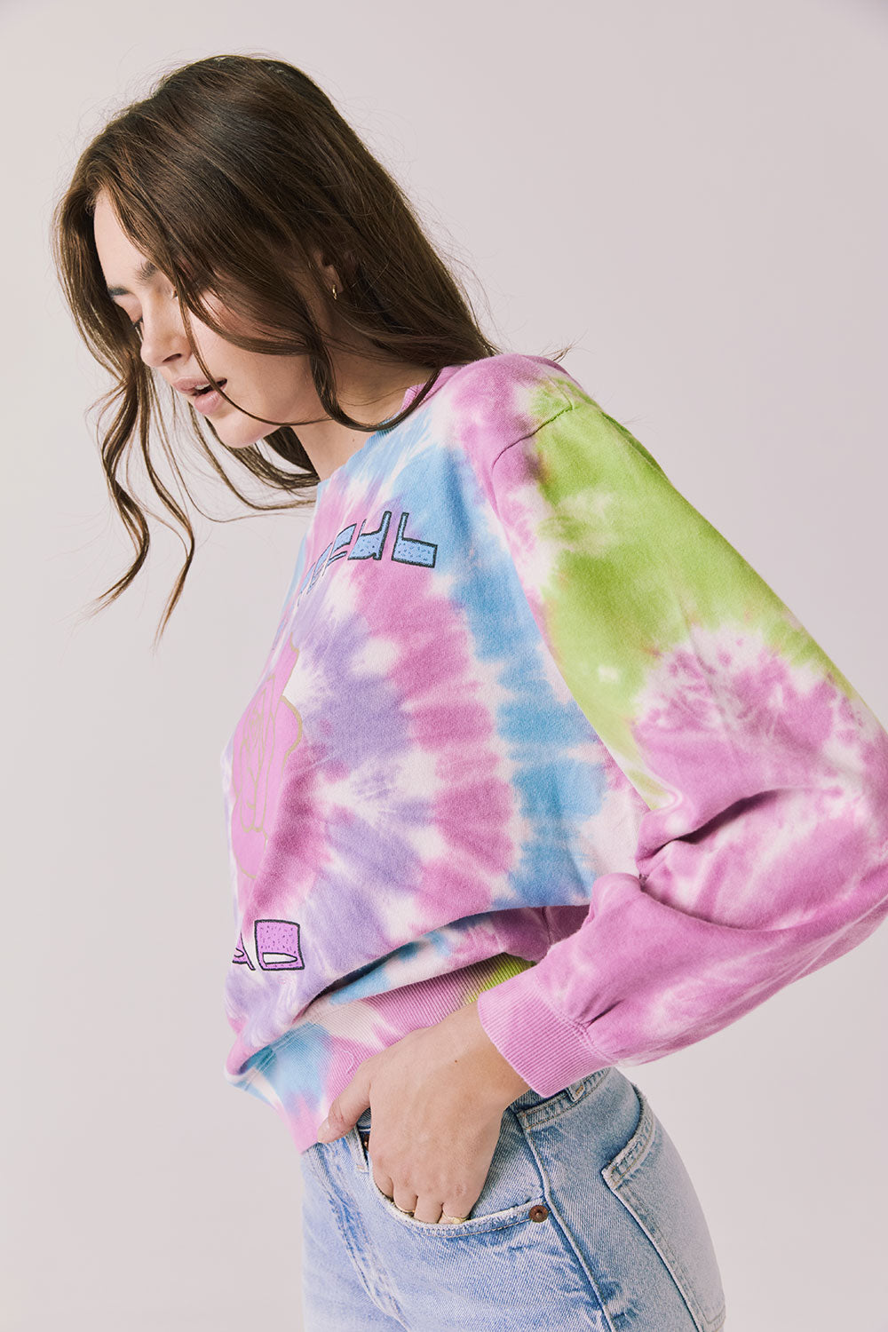 Side view of woman wearing Chaser’s Grateful Dead Rose Logo Long Sleeve with tie-dye pattern on a plain background