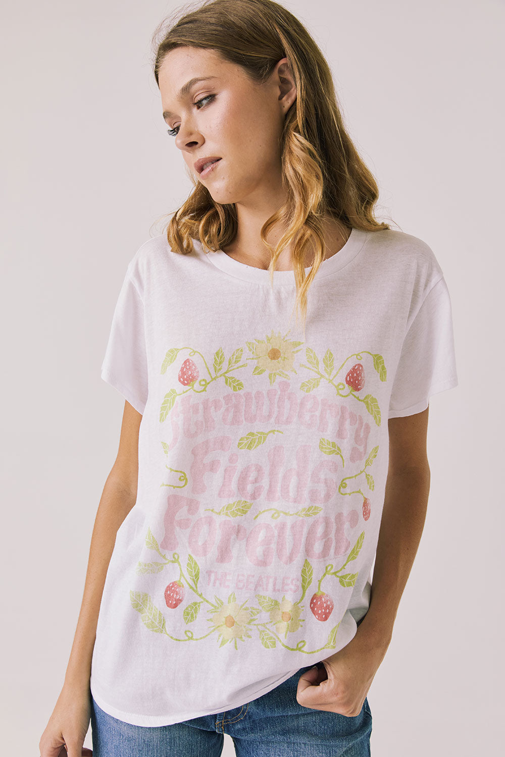 Front view of woman wearing Chaser’s The Beatles Strawberry Fields Forever White Tee with floral and pink text design on a plain background