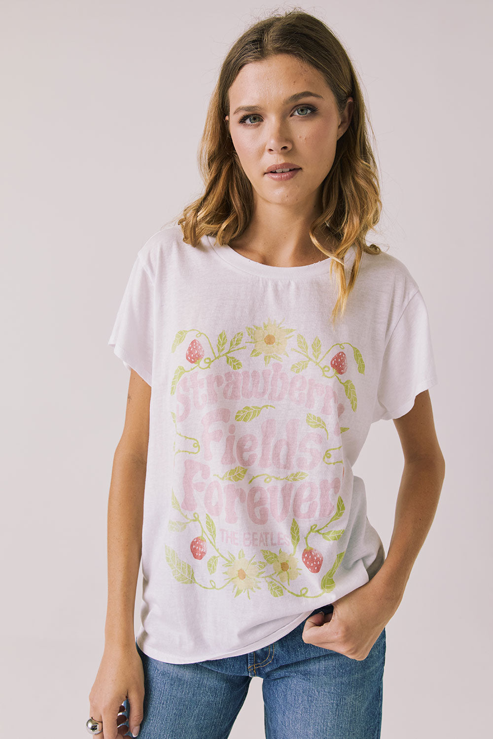Front view of woman wearing Chaser’s The Beatles Strawberry Fields Forever White Tee with floral and pink text design on a plain background