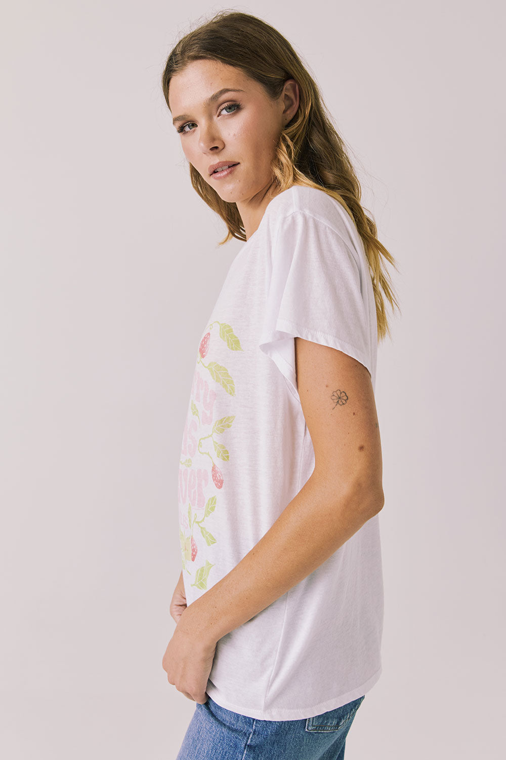 Side view of woman wearing Chaser’s The Beatles Strawberry Fields Forever White Tee on a plain background