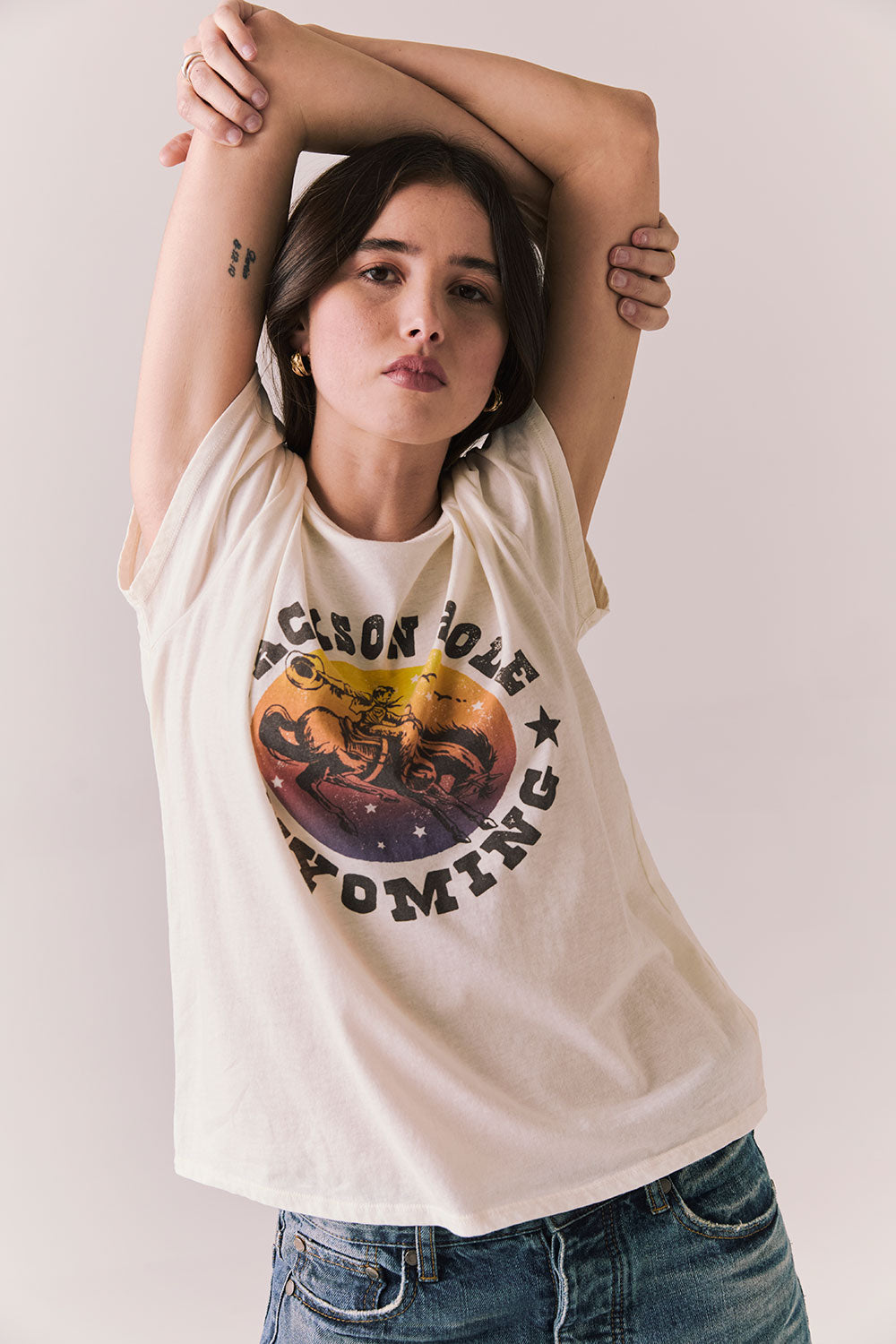 Front view of model wearing the Jackson Hole Sunset Tee in white with scenic Western graphic with graphic design on a plain background