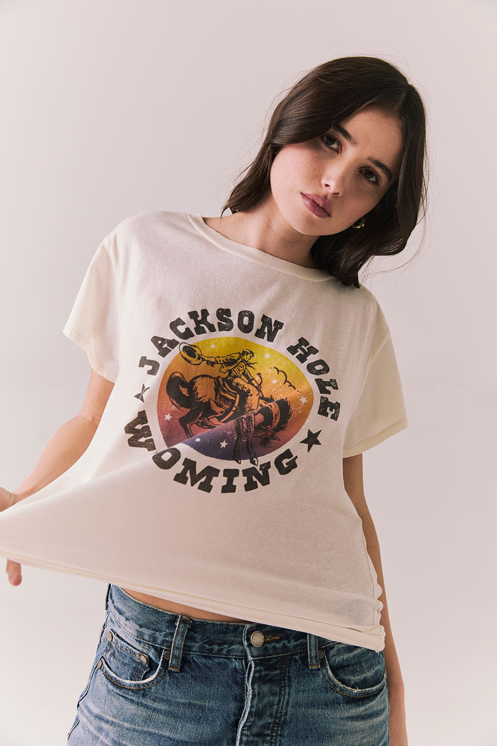 Front view of model wearing the Jackson Hole Sunset Tee in white with scenic Western graphic with graphic design on a plain background