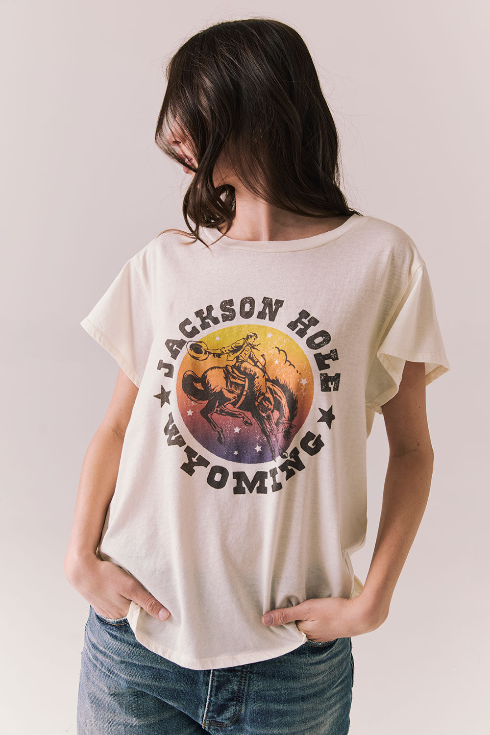 Front view of model wearing the Jackson Hole Sunset Tee in white with scenic Western graphic with graphic design on a plain background