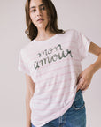 Front view of woman wearing Chaser’s white Mon Amour Stripe Tee with “mon amour” French text and light pink stripes on a plain background