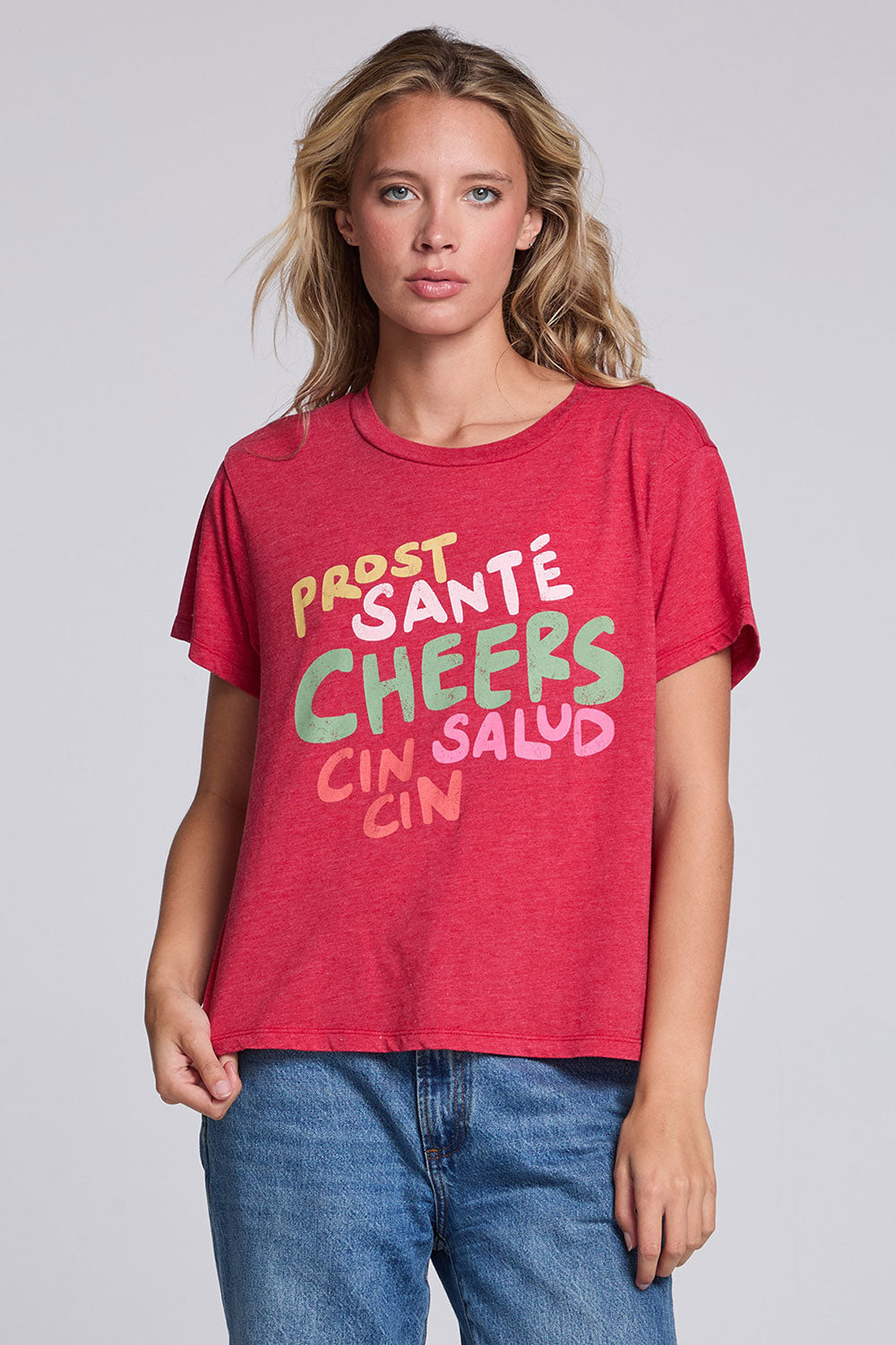 Model wearing Chaser's Cheers Tee in Cherry Bomb red with French-style celebratory lettering, front view