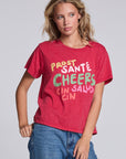 Model wearing Chaser's Cheers Tee in Cherry Bomb red with French-style celebratory lettering, angled view