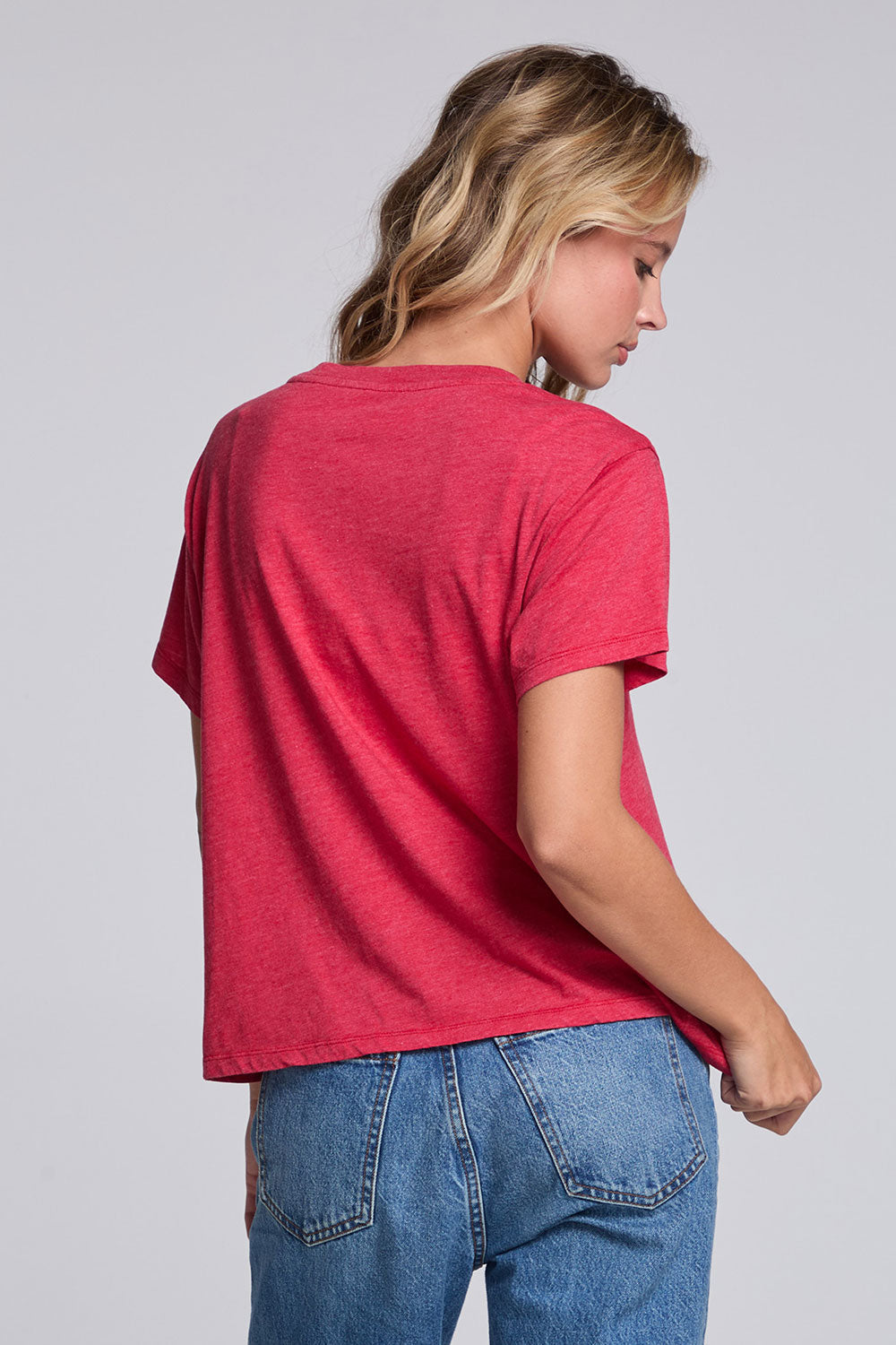 Model wearing Chaser's Cheers Tee in Cherry Bomb red with French-style celebratory lettering, back view