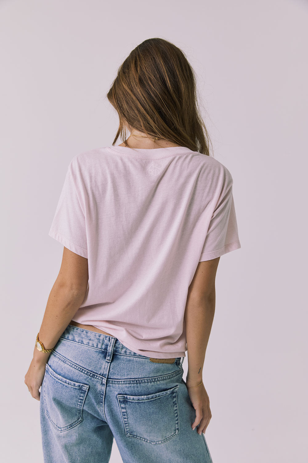 Back view of a woman wearing Chaser's the Grateful Dead 60 Years so Far pink tee on a plain background