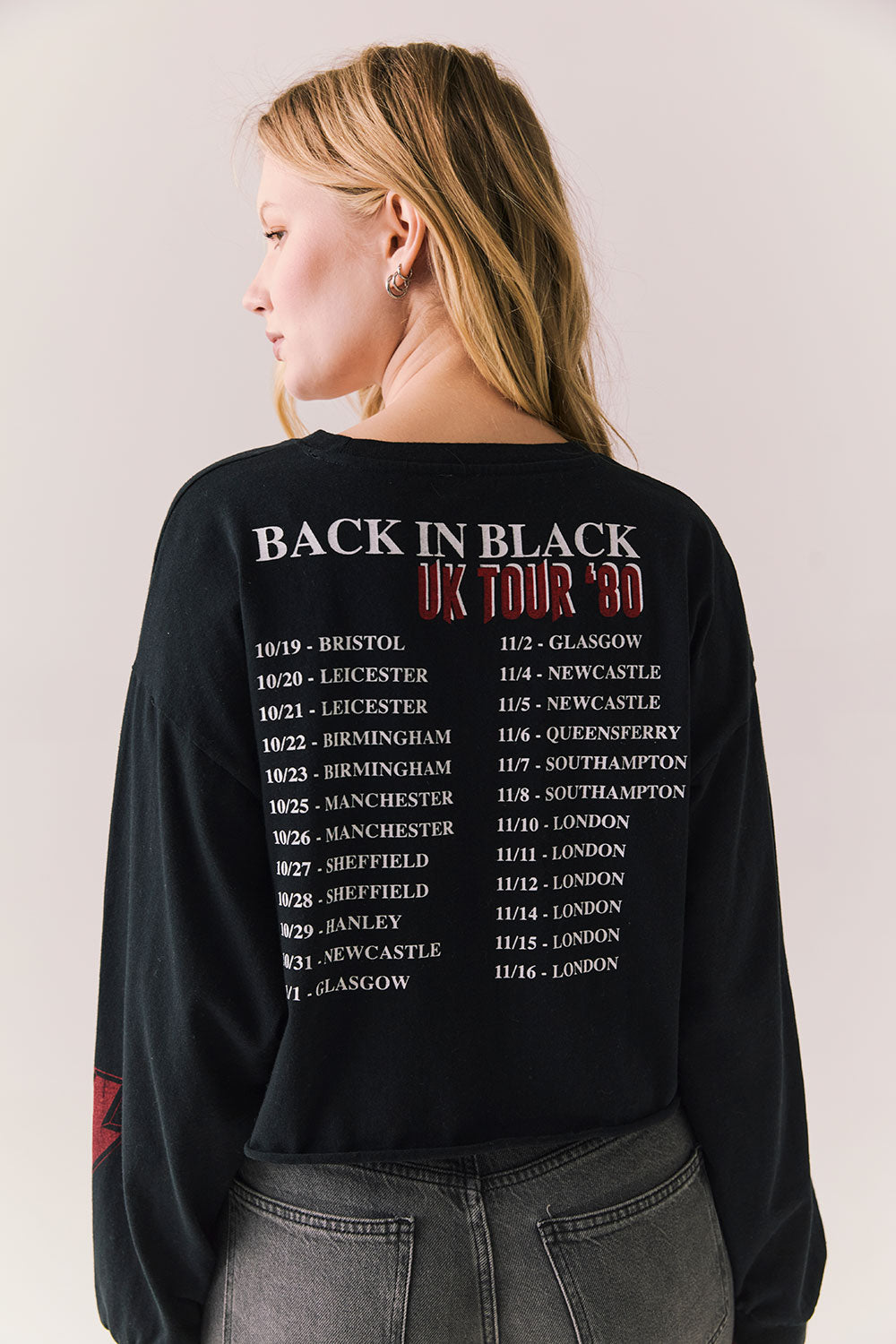 Back view of AC/DC UK Tour ’80 Tee in True Black with vintage UK Tour 1980 poster graphic and cropped long-sleeve fit on plain background