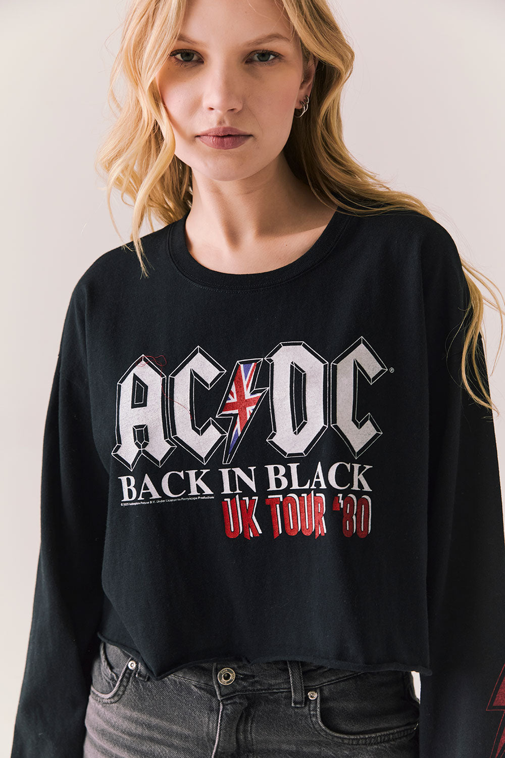 Front view of AC/DC UK Tour ’80 Tee in True Black with vintage UK Tour 1980 poster graphic and cropped long-sleeve fit on plain background
