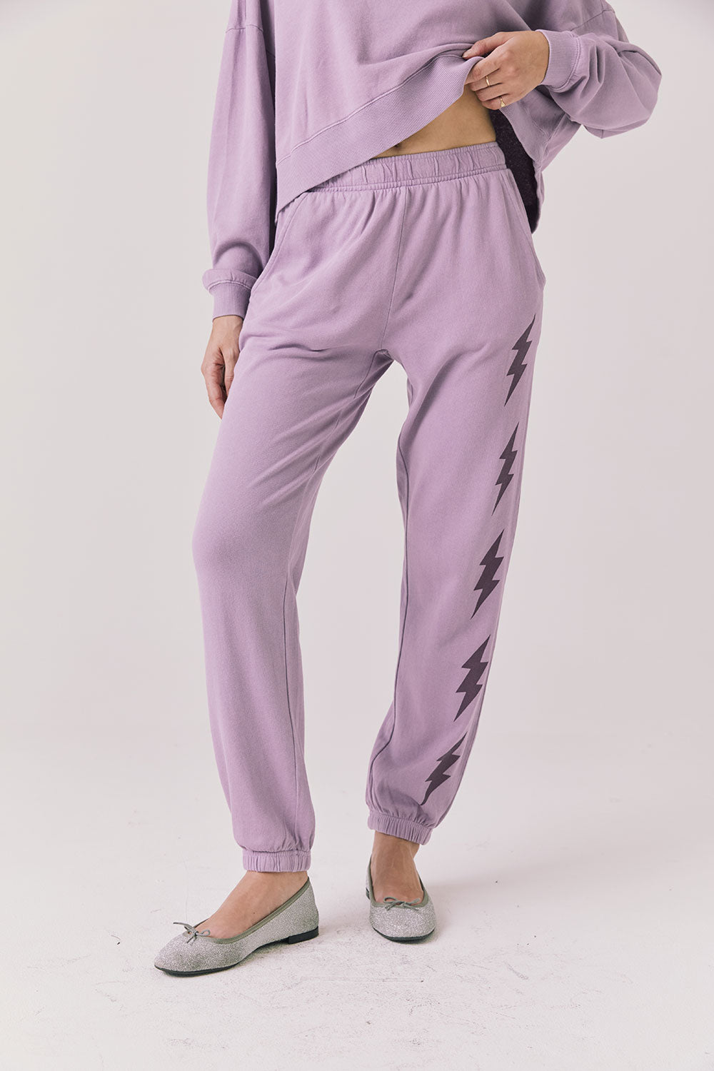 Woman wearing Chaser’s Bolt Amethyst Purple Joggers with matching pullover on a plain background