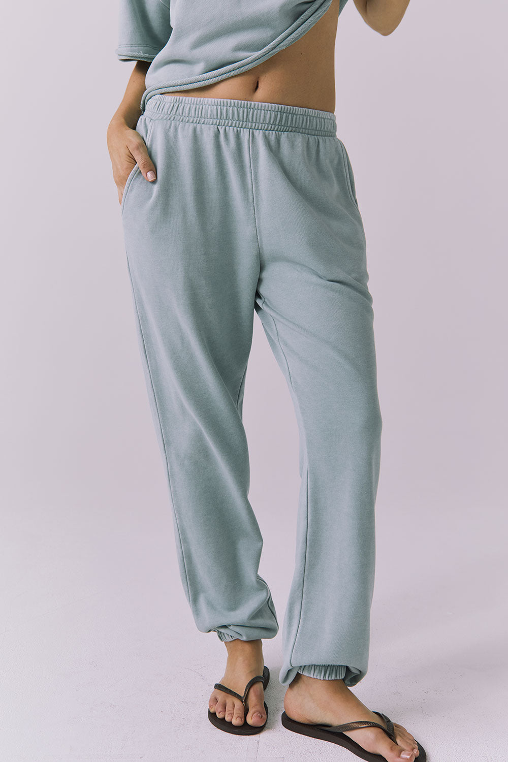 Front view of woman wearing Chaser's Mission Joggers in garden green sage on a plain background