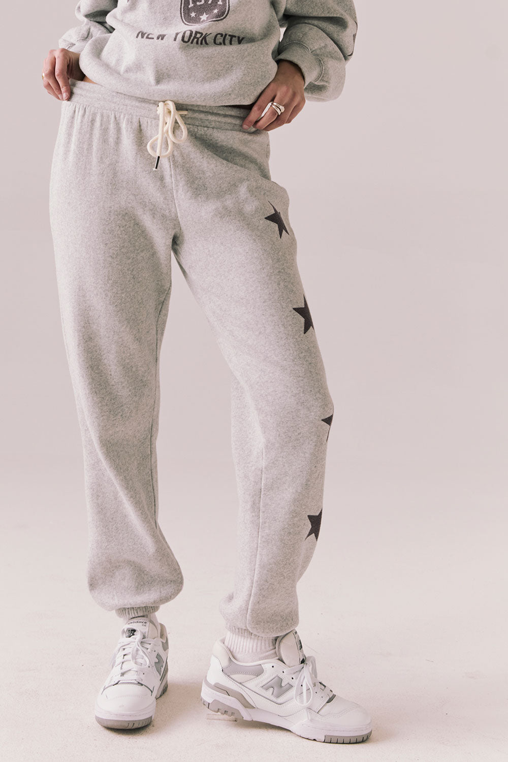 Front view of NYC Stars Joggers in Heather Grey with black star print down each leg, styled for a casual lounge look, against a plain background
