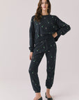 Full body view of woman wearing Chaser’s black Champagne Party Joggers with matching Champagne Party Pullover on a light grey background