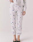 Full body view of woman wearing Chaser’s Festive Stars Joggers in light grey with star patterns and matching top on a white background