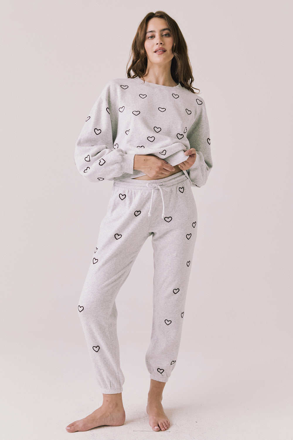 Full body view of woman wearing Chaser’s light grey Tossed Hearts Pants with matching Tossed Hearts Long Sleeve top on a white background