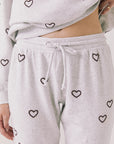 Front view of woman wearing Chaser’s light grey Tossed Hearts Pants with small heart patterns on a white background