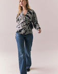 Full body view of model in black tie dye hoodie and blue jeans on a plain background