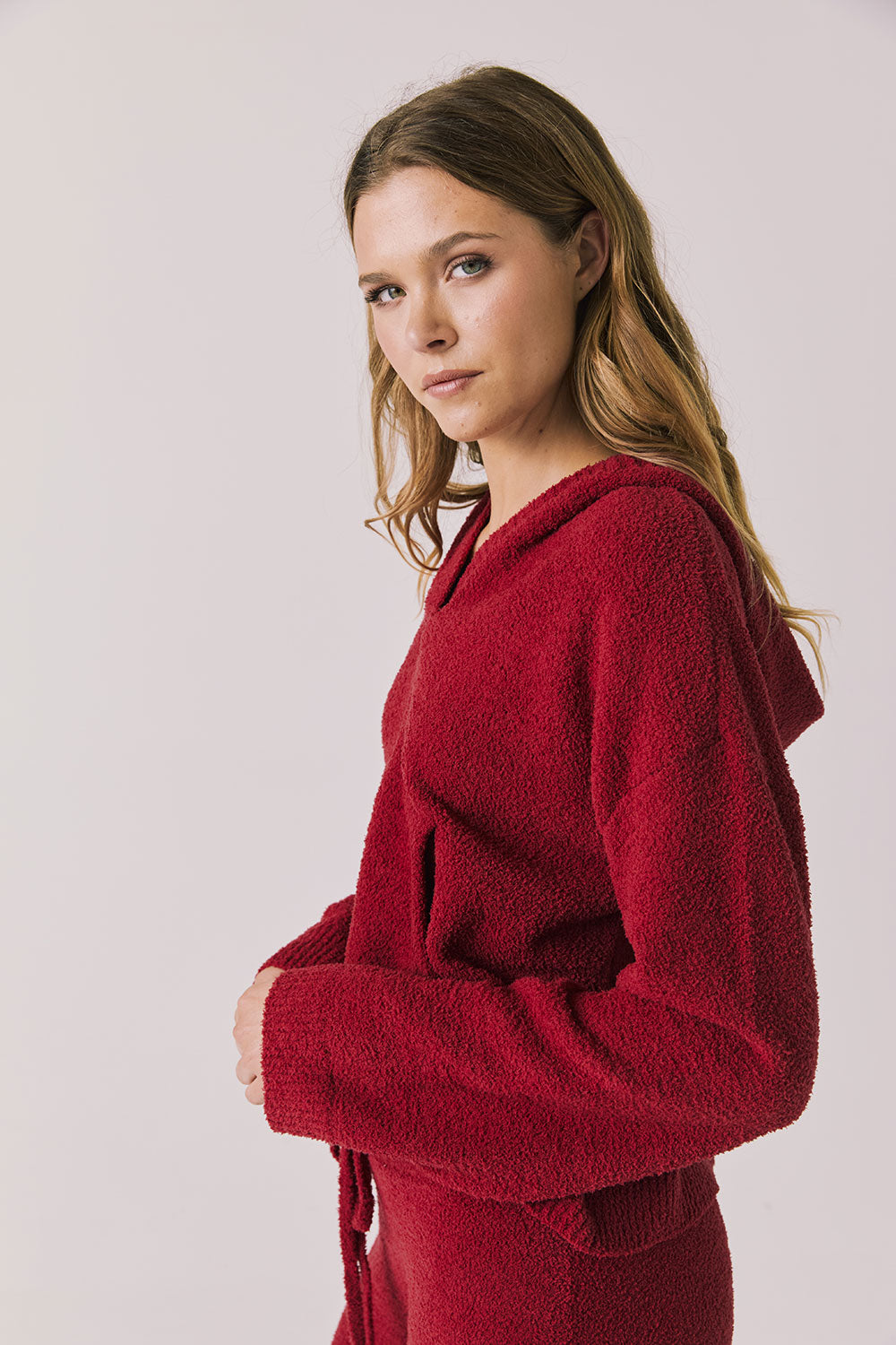 Side view of woman wearing Chaser’s Hazen Purple-Red Fig Pullover Hoodie on a white background