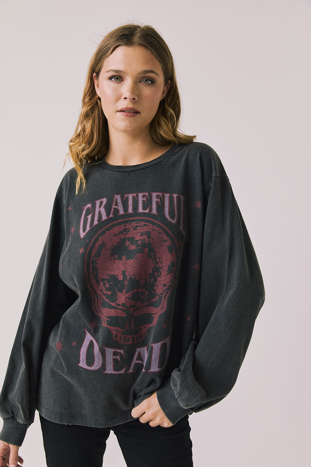 Front view of woman wearing Chaser’s Grateful Dead Disco Stealie Long Sleeve with a skull design on a plain background