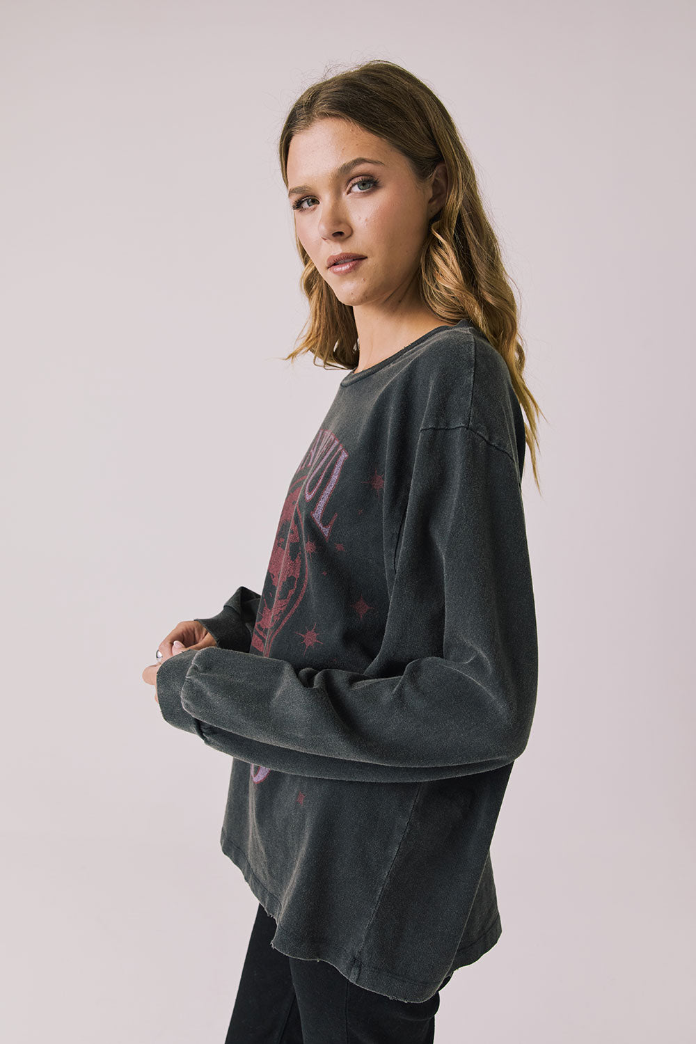 Side view of woman wearing Chaser’s Grateful Dead Disco Stealie Long Sleeve with a skull design on a plain background
