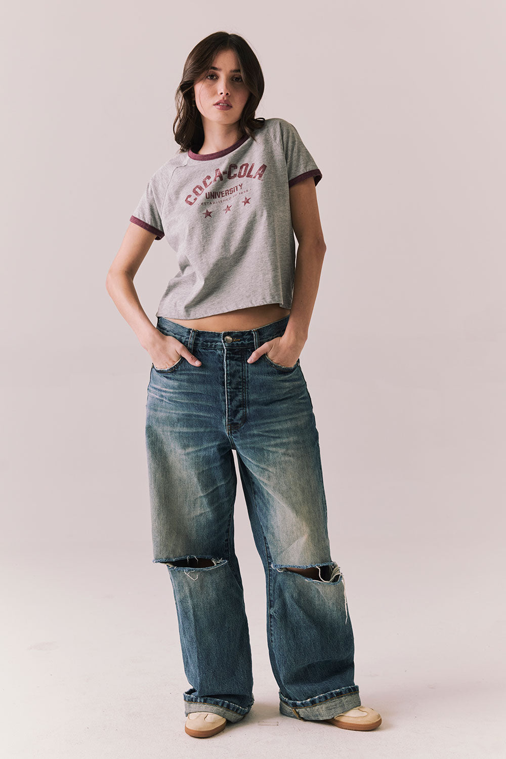  Full body view of model in Coca-Cola heather grey ringer tee and denim